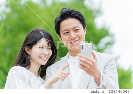 屋外でスマホを見るカップル・夫婦 屋外でスマホを見るカップル・夫婦 105546042