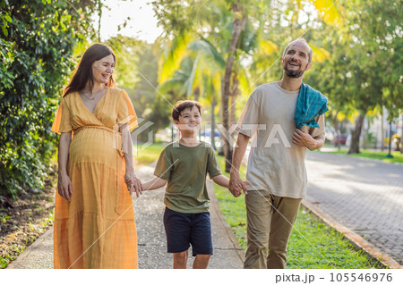 A loving family enjoying a leisurely walk in the park - a radiant pregnant woman after 40, embraced by her husband, and accompanied by their adult teenage son, savoring precious moments together 105546976