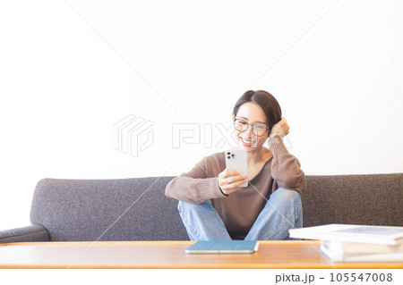 ソファに座ってスマホを見る女性 105547008