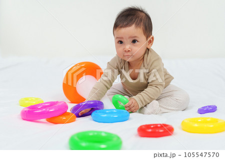 infant baby playing the pyramid toy with colored rings on bed infant baby playing the pyramid toy with colored rings on bed 105547570