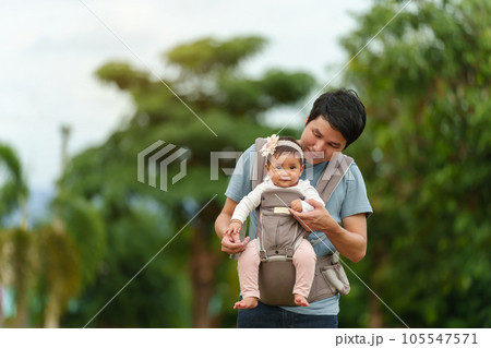 father playing with infant in baby carrier in park 105547571