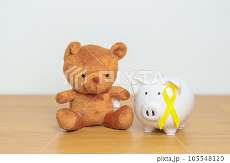 International Childhood Cancer Awareness month, Children toy with golden yellow color Ribbon with Piggy Bank for Donation, Charity, Campaign, Money Saving, Fund and World cancer day concept 105548120