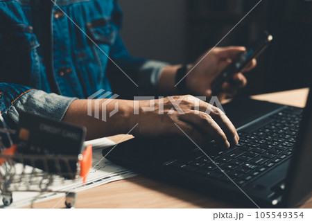 Man using smartphone and computer laptop. which is payment online, sits on the chair in the office at home on a desktop. The concept of finance and online shopping. 105549354