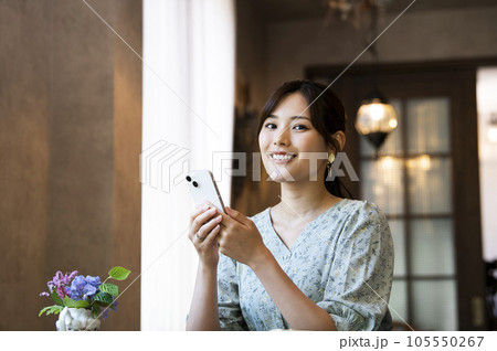 カフェでスマホを操作する女性　カメラ目線 105550267