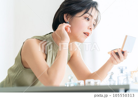 メイクルームでコンパクトを見てメイクをするショートヘアの若い女性 105550313