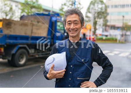 工事現場の前に笑顔で立つ職人 105553911