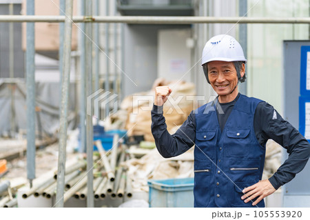 工事現場の前に笑顔で立つ職人 105553920