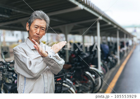 駐輪場でバツ印を見せる管理者のシニア男性 駐輪場でバツ印を見せる管理者のシニア男性 105553929