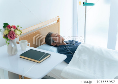 酸素チューブをつけてベッドに寝るシニア男性 105553957