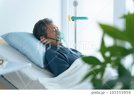 酸素マスクをつけてベッドに寝るシニア男性 105553959