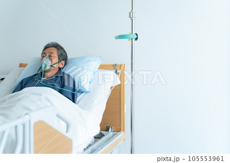 酸素マスクをつけてベッドに寝るシニア男性 105553961