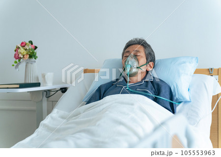 酸素マスクをつけてベッドに寝るシニア男性 105553963