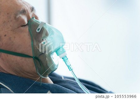酸素マスクをつけてベッドに寝るシニア男性 105553966