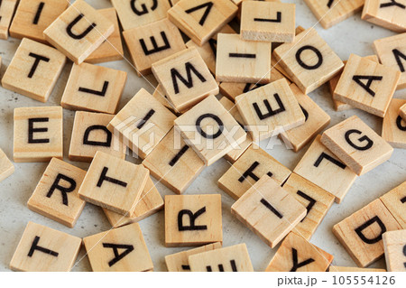 Pile of wooden tiles with various letters scattered on white stone like board, closeup view from above 105554126
