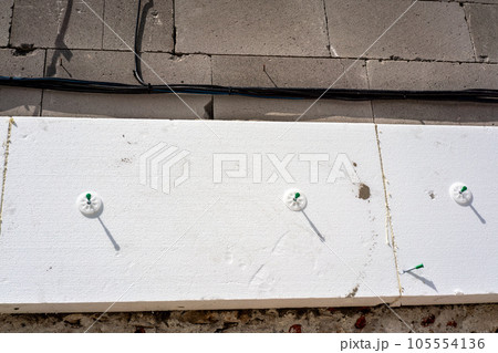 White polystyrene foam board blocks for heat insulation on bare concrete wall at construction site, closeup detail White polystyrene foam board blocks for heat insulation on bare concrete wall at construction site, closeup detail 105554136