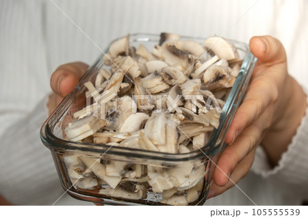 Unrecognizable woman showing into camera frozen food sliced mushrooms champignon homemade. Harvesting concept. Stocking up vegetables for winter storage Unrecognizable woman showing into camera frozen food sliced mushrooms champignon homemade. Harvesting concept. Stocking up vegetables for winter storage 105555539
