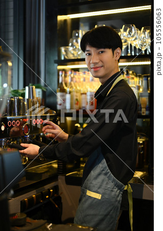 Smiling male barista preparing coffee for customer order in trendy coffee. Small business concept. Smiling male barista preparing coffee for customer order in trendy coffee. Small business concept. 105556063