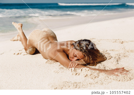 Naked woman enjoy at tropical ocean beach. Attractive nudist lady with perfect tanned body Naked woman enjoy at tropical ocean beach. Attractive nudist lady with perfect tanned body 105557402