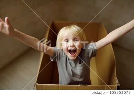 Cute preschool boy playing in a cardboard box during family's move to a new home. Kids play is a way of development of creative abilities. Cute preschool boy playing in a cardboard box during family's move to a new home. Kids play is a way of development of creative abilities. 105558075