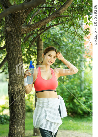 a young woman wearing summer morning sportswear and carrying a water bottle 105559286