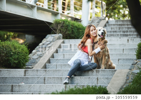 In the park, a lovely dog and a beautiful woman in sportswear are exercising together. In the park, a lovely dog and a beautiful woman in sportswear are exercising together. 105559559