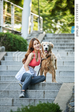 In the park, a lovely dog and a beautiful woman in sportswear are exercising together. 105559560