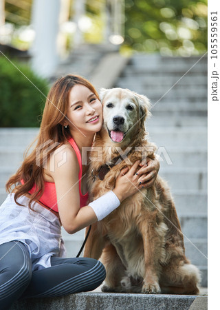 In the park, a lovely dog and a beautiful woman in sportswear are exercising together. 105559561