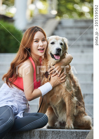 In the park, a lovely dog and a beautiful woman in sportswear are exercising together. 105559562