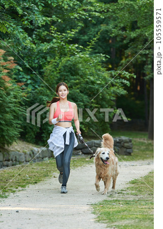 In the park, a lovely dog and a beautiful woman in sportswear are exercising together. In the park, a lovely dog and a beautiful woman in sportswear are exercising together. 105559571