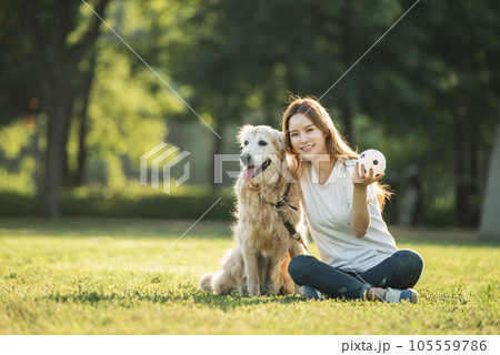 a beautiful woman playing ball with her dog in the park a beautiful woman playing ball with her dog in the park 105559786