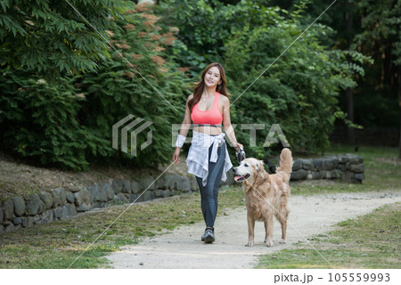 In the park, a lovely dog and a beautiful woman in sportswear are exercising together. In the park, a lovely dog and a beautiful woman in sportswear are exercising together. 105559993