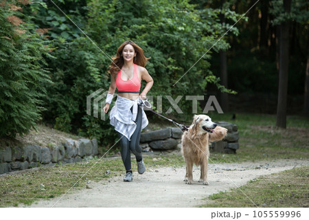 In the park, a lovely dog and a beautiful woman in sportswear are exercising together. 105559996