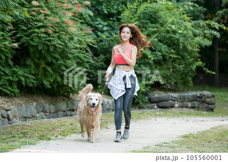 In the park, a lovely dog and a beautiful woman in sportswear are exercising together. 105560001