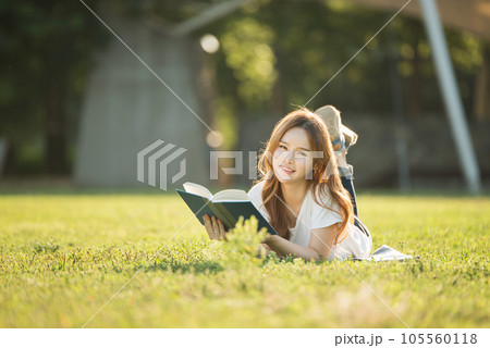 a beautiful woman lying on the park lawn reading a beautiful woman lying on the park lawn reading 105560118