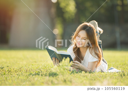 a beautiful woman lying on the park lawn reading a beautiful woman lying on the park lawn reading 105560119