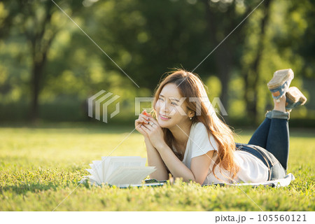 a beautiful woman lying on the park lawn reading a beautiful woman lying on the park lawn reading 105560121