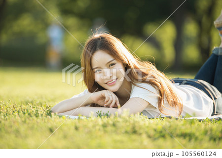 a beautiful woman lying on the park lawn reading a beautiful woman lying on the park lawn reading 105560124