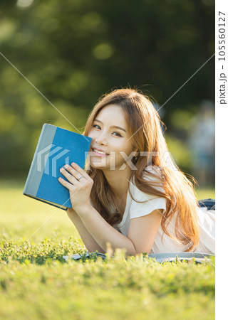 a beautiful woman lying on the park lawn reading a beautiful woman lying on the park lawn reading 105560127