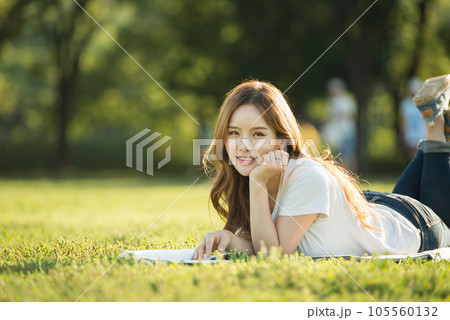a beautiful woman lying on the park lawn reading a beautiful woman lying on the park lawn reading 105560132