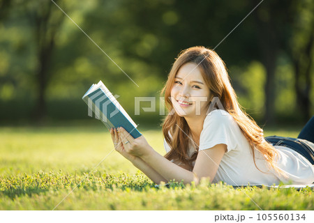 a beautiful woman lying on the park lawn reading a beautiful woman lying on the park lawn reading 105560134