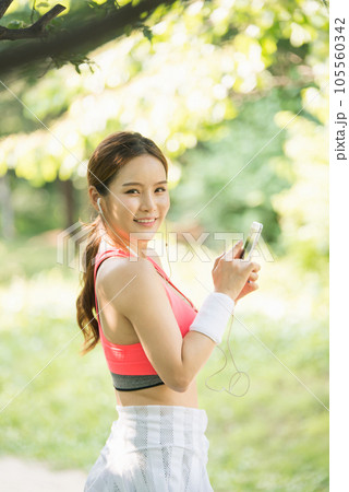 A beautiful woman wearing sportswear and exercising while listening to music on her smartphone in the park 105560342