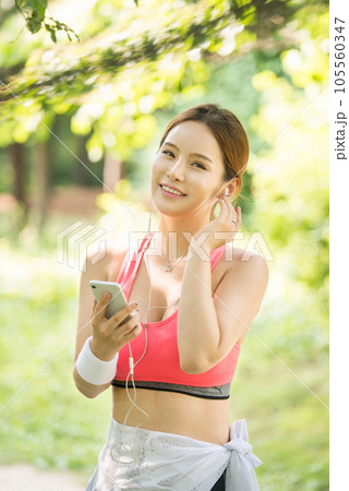A beautiful woman wearing sportswear and exercising while listening to music on her smartphone in the park 105560347