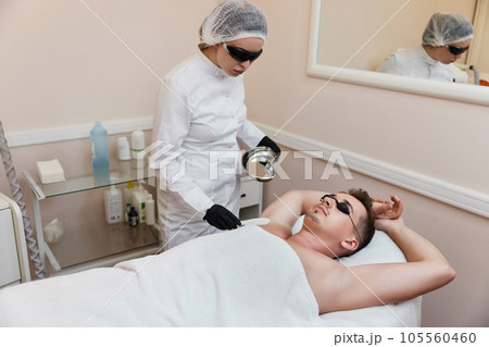young man undergoes procedure of arm pit laser epilation young man undergoes procedure of arm pit laser epilation 105560460