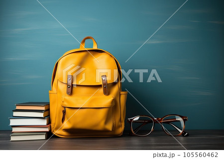 Yellow backpack with glasses and stack of books on table. Education or Back to school concept. 105560462