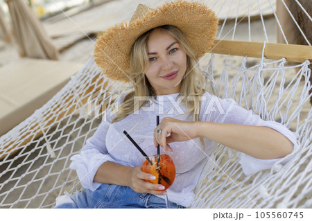 woman with cocktail relaxed in hammock woman with cocktail relaxed in hammock 105560745