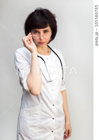 Woman doctor through glasses looks at the camera, close-up Woman doctor through glasses looks at the camera, close-up 105560785
