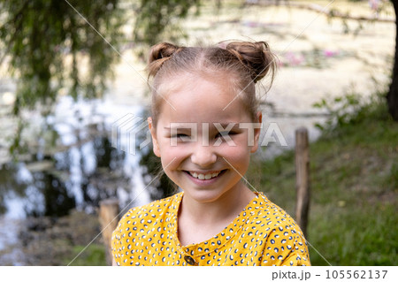 Lovely small girl sitting on a bench in the park and smiling at camera. 105562137