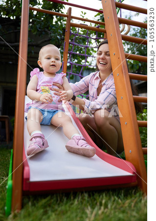 little baby girl with mother on slide in playground 105563230