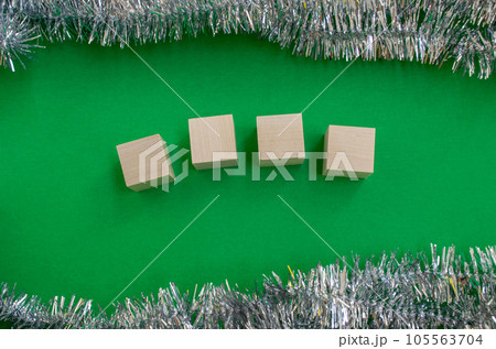 New Year's card template. Wooden cubes for the number of the year, tinsel on a green background. New Year's card template. Wooden cubes for the number of the year, tinsel on a green background. 105563704