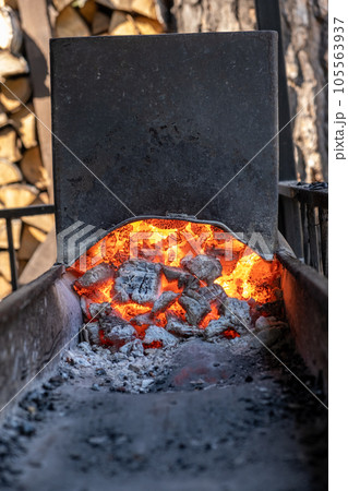 Burning coals in a metal grill for frying meat and vegetables. Cooking on a campfire. Burning coals in a metal grill for frying meat and vegetables. Cooking on a campfire. 105563937